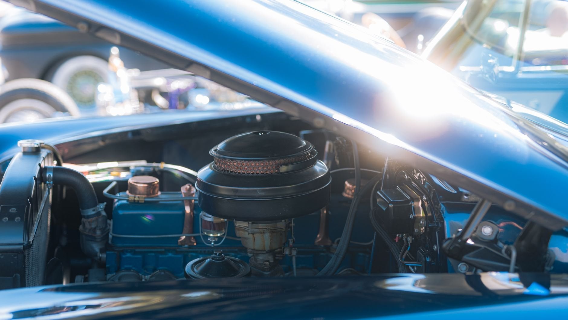 Close-up view of a classic vintage car engine under the hood, showcasing intricate automotive details.