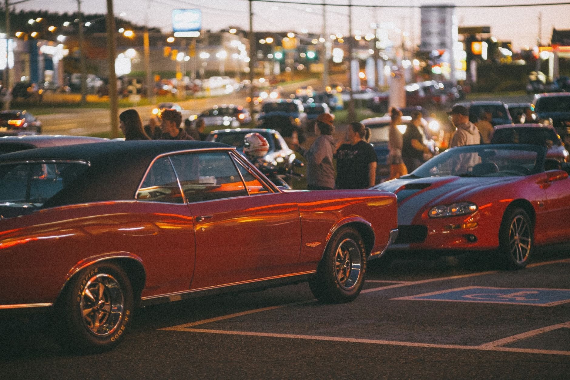 A lively gathering of classic car enthusiasts showcasing vintage models at night.